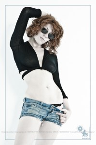 Sexy Jeans - Classic White Style with beautiful model wearing tight short jeans hotpants and half transparent black top showing hear sting looking through sun glasses - © by Magistus