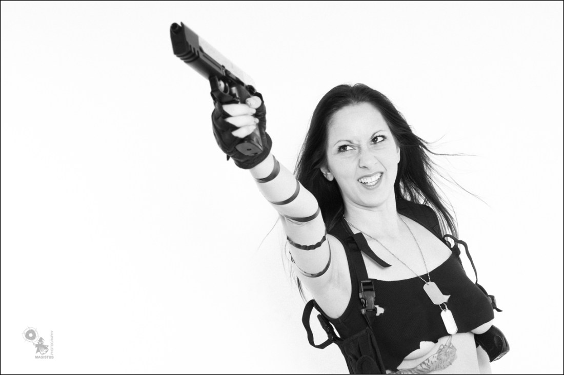 Action Shooter - Sexy Fightergirl Black & White Photo with a busty girl in a very small top posing with a big gun showing a litte bit auf her big boobs. - © by Magistus