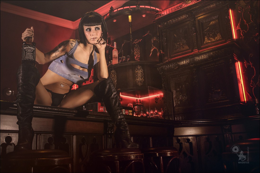 Sexy Barkeeper - Erotic OnLocation Photoshoot with fantastic big busted model posing hot with a bottle of whisky - © by Magistus